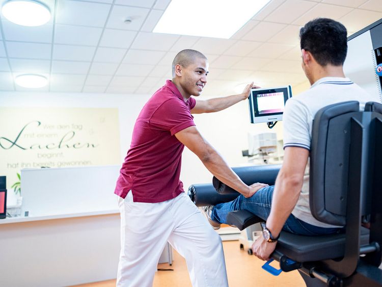 Therapeut unterstützt Patient in der Medizinische Trainingtherapie