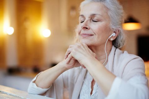 Eine Frau hört zu Hause einen Podcast