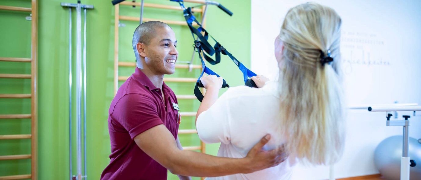 Therapeut unterstützt Patientin beim Training