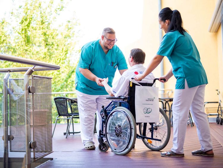 Pflegekräfte kümmern sich um Patienten im Rollstuhl