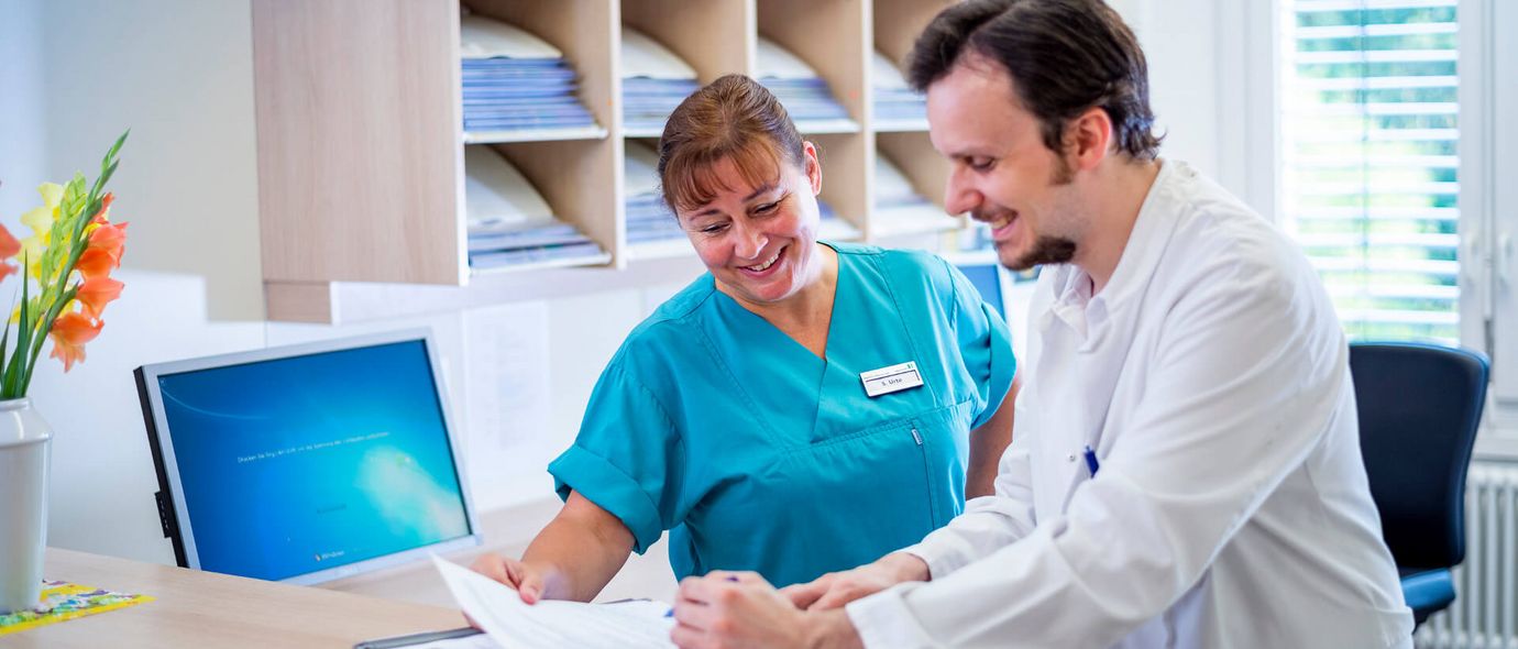 Arzt und Pflegekraft besprechen Patientenakten