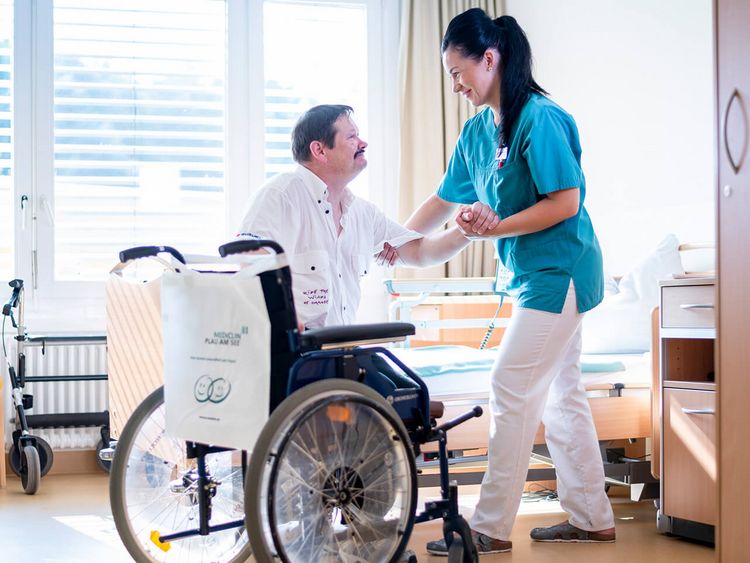 Pflegerin kümmert sich um Patienten im Rollstuhl