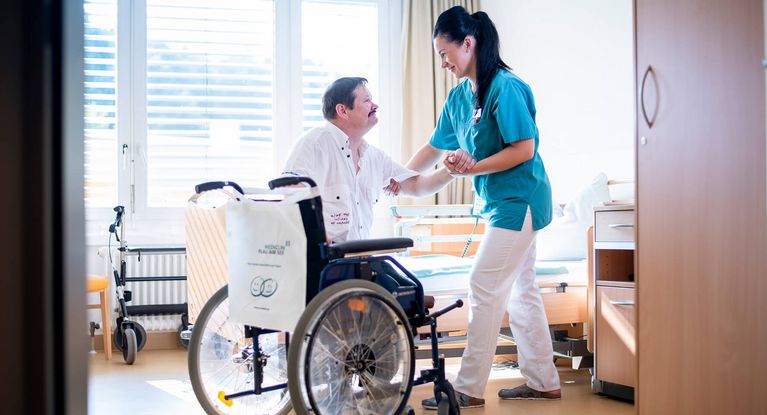 Pflegerin kümmert sich um Patienten im Rollstuhl